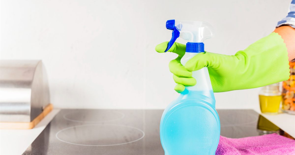 Person wearing gloves and spraying a kitchen surface