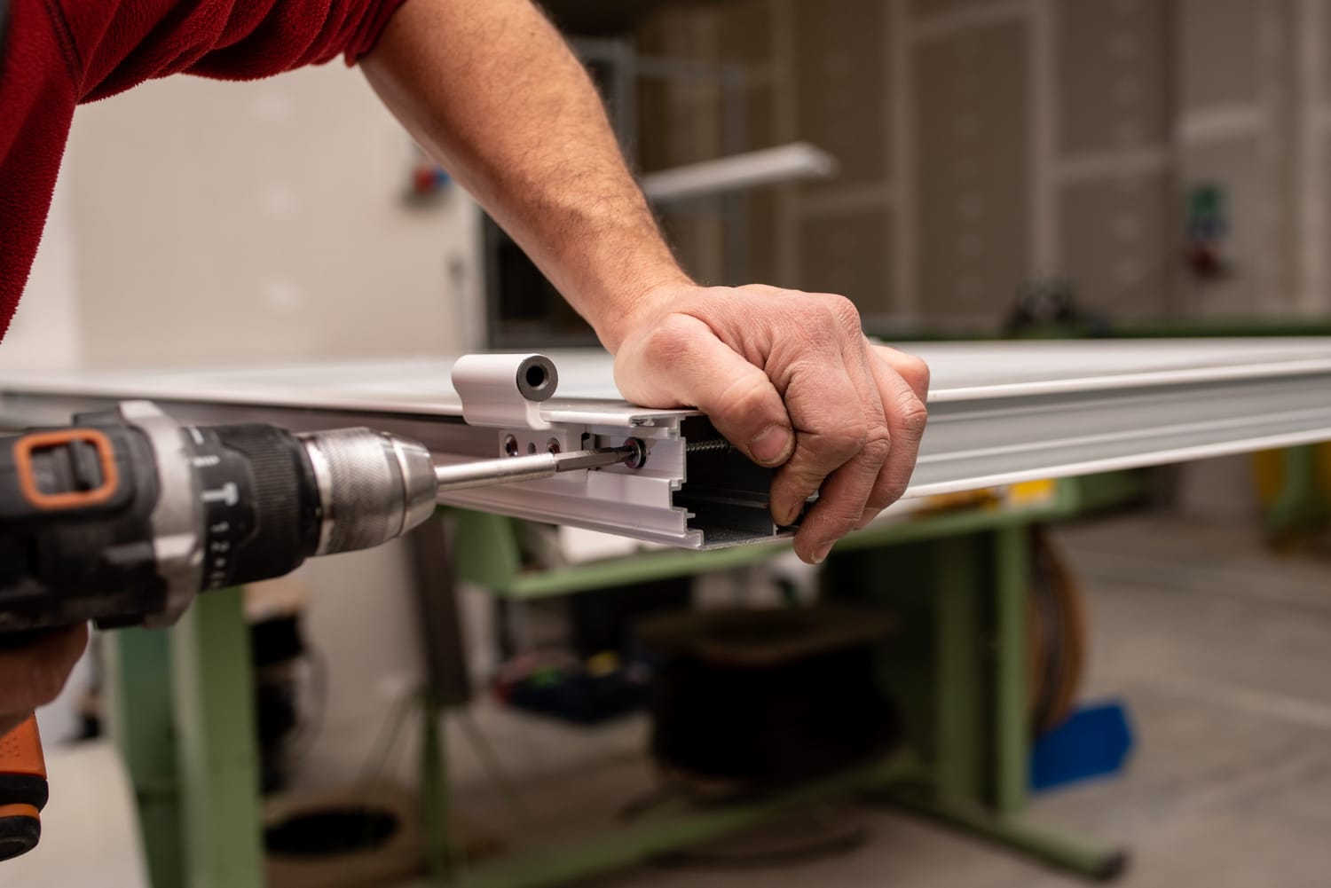 Worker fastening hardware to a frame profile in a workshop