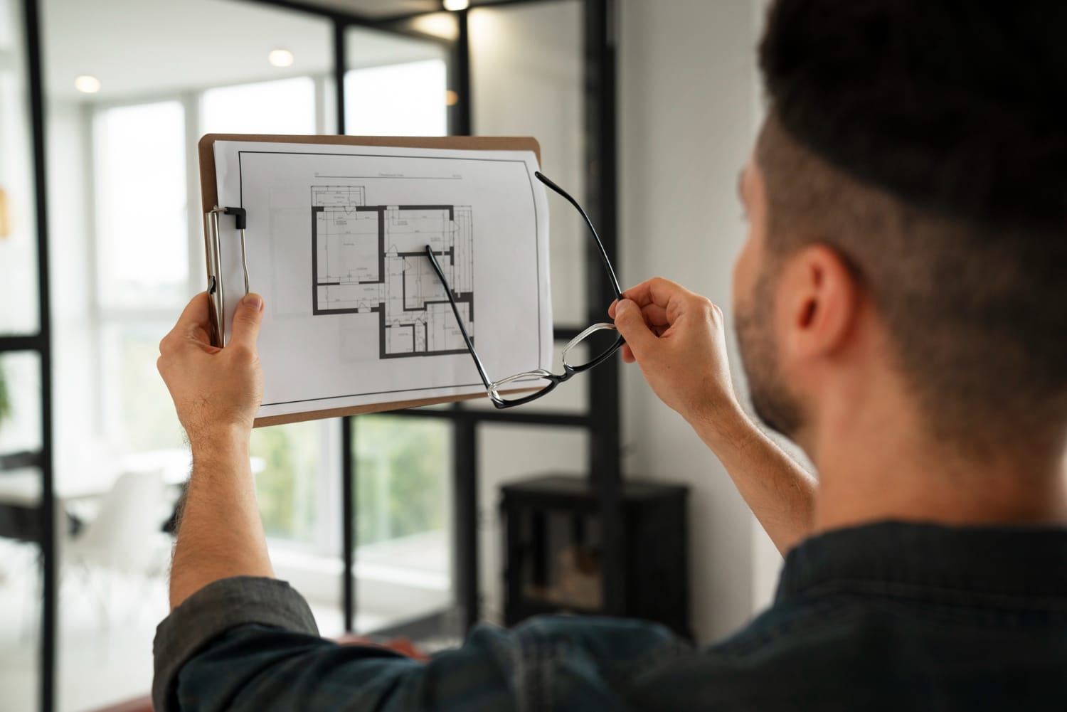 Person reviewing a floor plan beside framed glazing