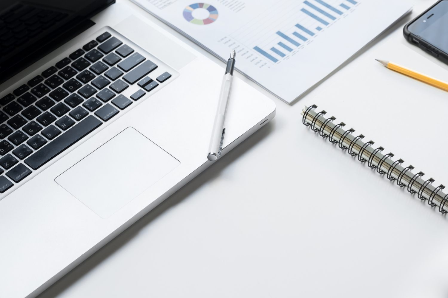 Laptop beside printed business charts